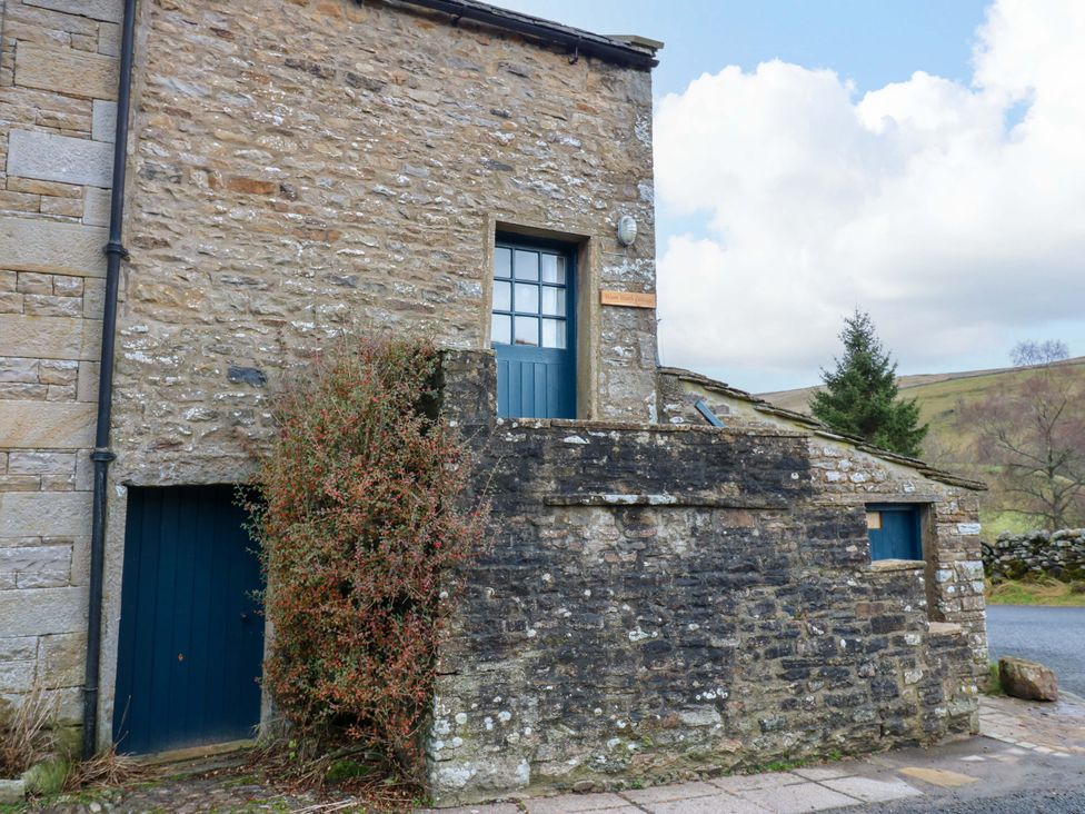 An outdoor area of a building with stone walls and a blue door at Wain Wath Cottage in Richmond
