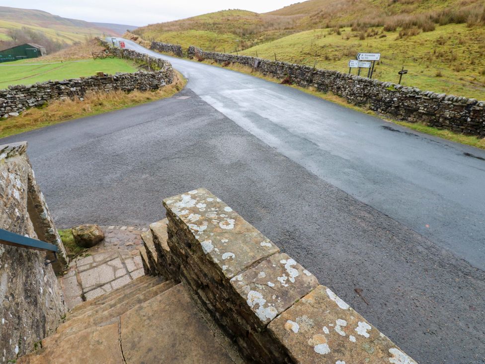 A view of a road and stone wall from steps at Wain Wath Cottage in Richmond