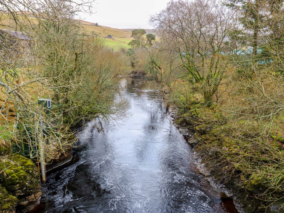 A view of a river surrounded by trees and grass at Wain Wath Cottage in Richmond