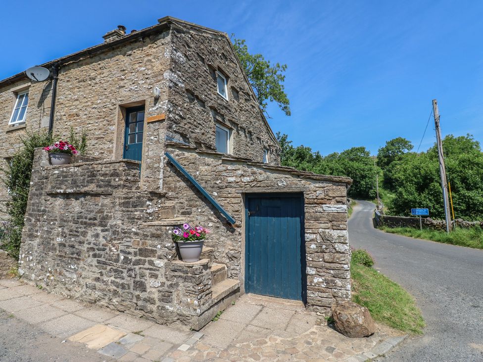 A stone building with a blue door and flower pots at Wain Wath Cottage Keld near Muker