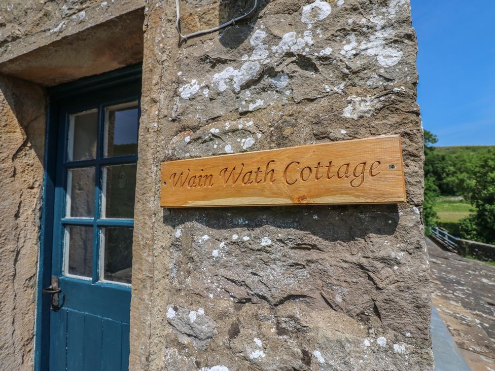 A sign for Wain Wath Cottage on a stone wall at Wain Wath Cottage Keld near Muker