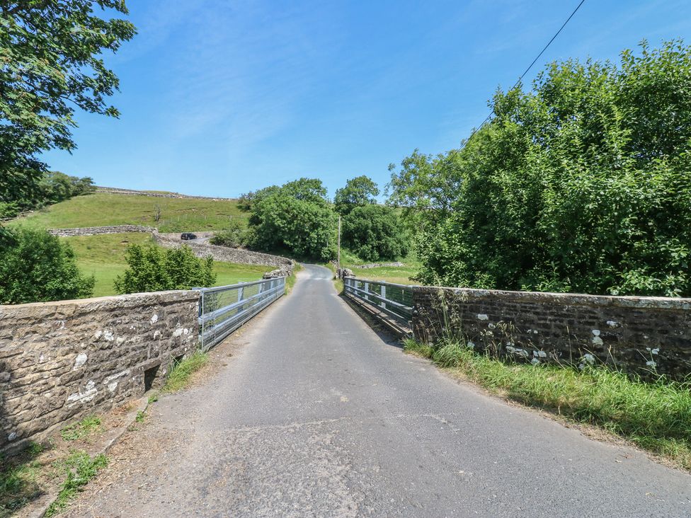 A bridge over a road leading to fields and trees at Wain Wath Cottage in Keld near Muker