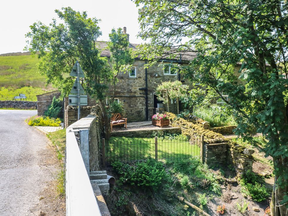 A stone house with a garden and bench at Wain Wath Cottage in Keld near Muker