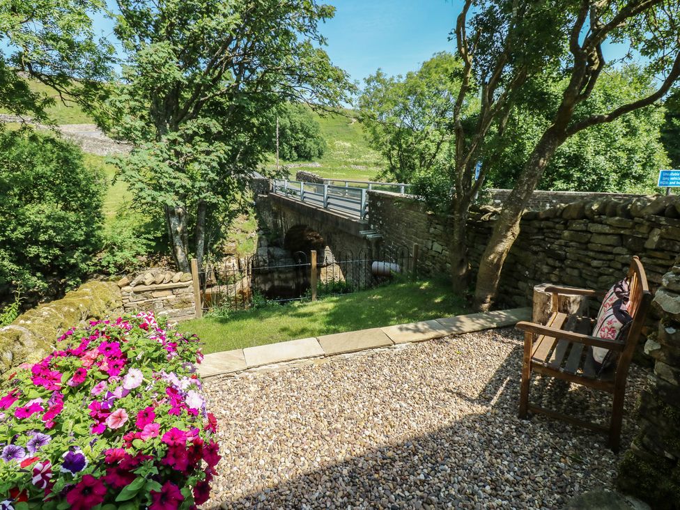 An outdoor area with a bench and flowers at Wain Wath Cottage in Keld near Muker