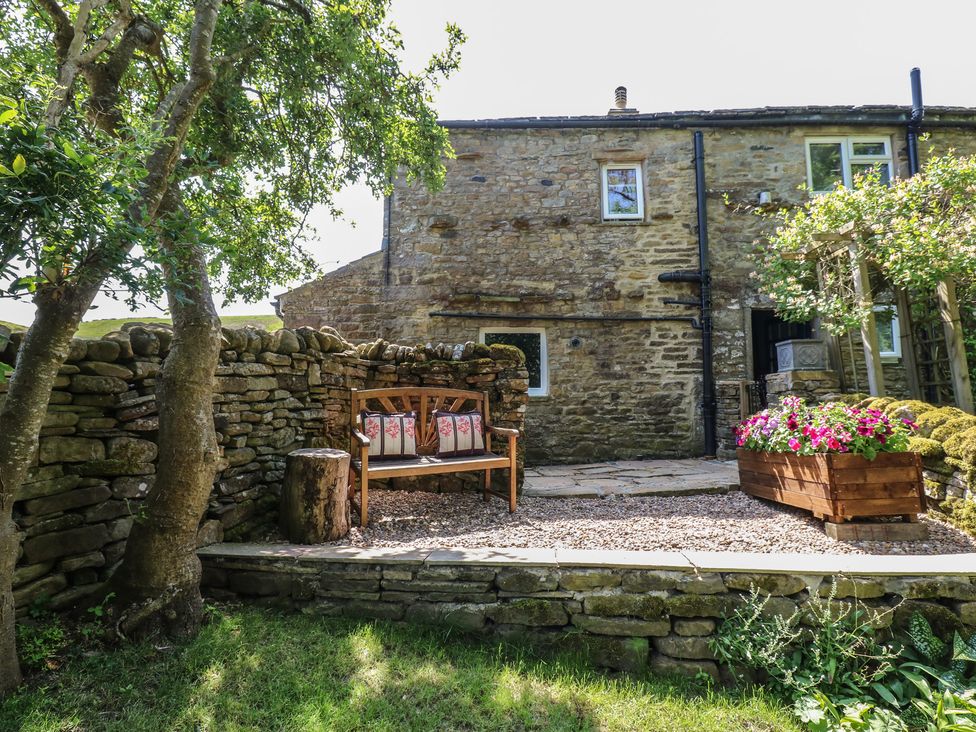 A garden with a bench and flower planter at Wain Wath Cottage in Keld near Muker