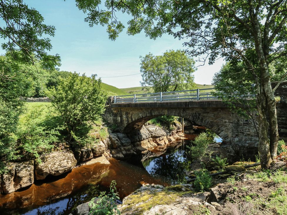 A bridge over a stream surrounded by trees at Wain Wath Cottage Keld near Muker