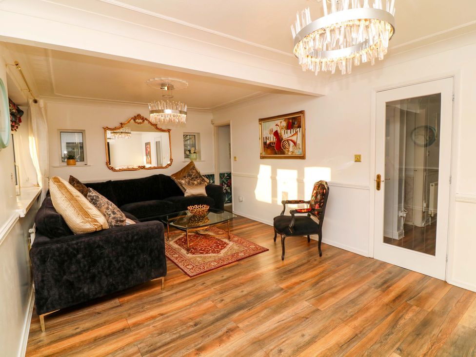 A living room with a sofa, coffee table, and chandelier at 12 Wyndham Road in Loughborough