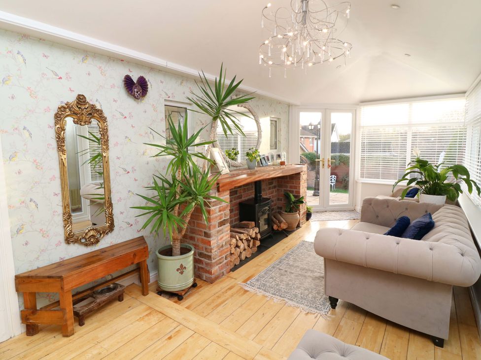A conservatory with a sofa and wooden fireplace at 12 Wyndham Road, Loughborough