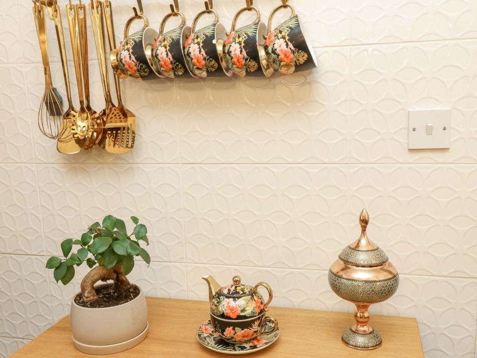 A kitchen area with utensils, cups, plant, teapot, and decorative jar at 12 Wyndham Road Loughborough