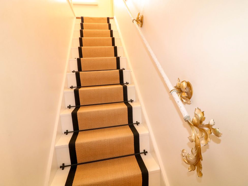 A staircase with a carpet runner and decorative handrail at 12 Wyndham Road, Loughborough