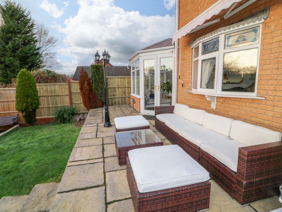 A garden with patio furniture and a conservatory at 12 Wyndham Road Loughborough