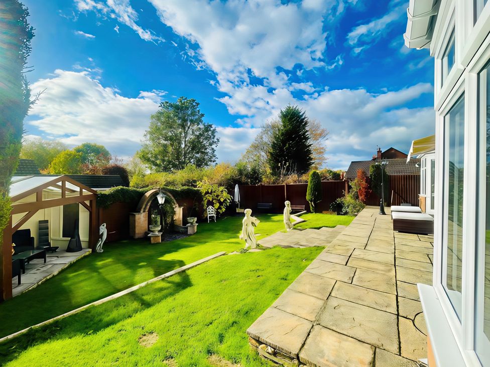 A garden with patio furniture and decorative statues at Ivy's End in Loughborough