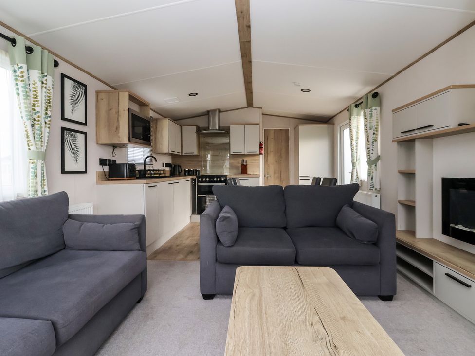 A living room with sofas and a kitchen area at The Driftwood near High Skirlington