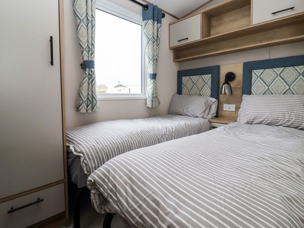 A bedroom with two beds and a nightstand at The Driftwood in High Skirlington near Skipsea