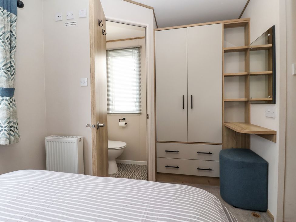 A bedroom with a cupboard and a mirror at The Driftwood near High Skirlington