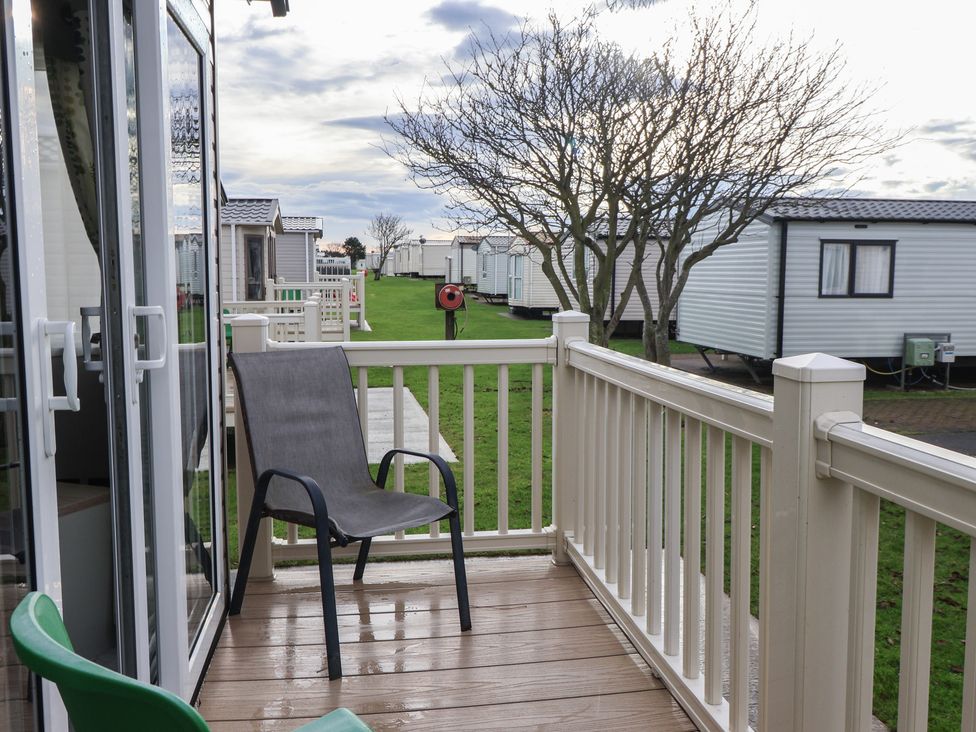 A balcony with a chair overlooking caravans at The Driftwood in High Skirlington near Skipsea