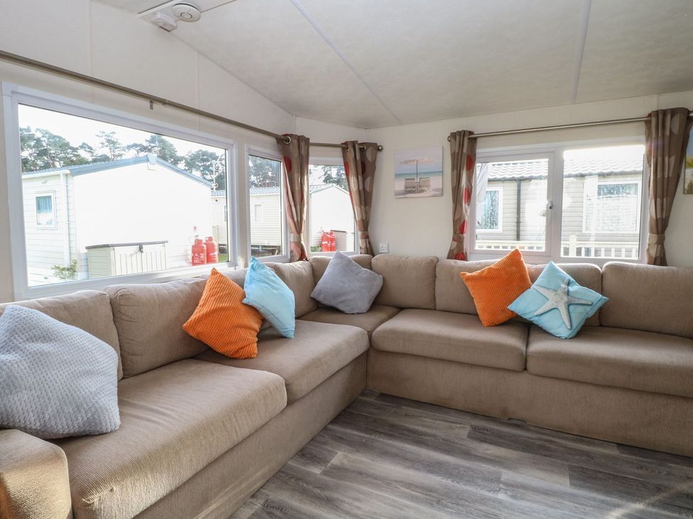 A living room with a sectional sofa and windows at 46 Foxburrow Hang in Great Yarmouth