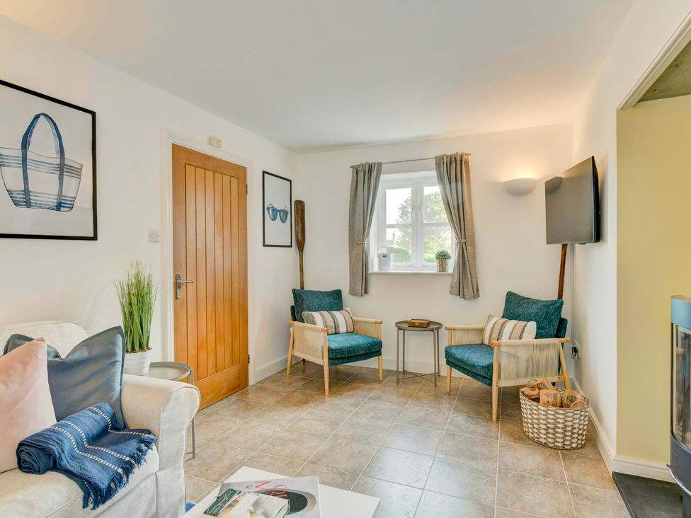 A living room with armchairs and a TV at The Old Boat House in Lyme Regis