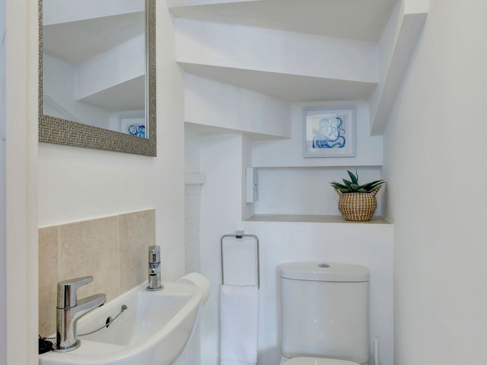 A bathroom with sink, toilet, and wall art at The Old Boat House in Lyme Regis