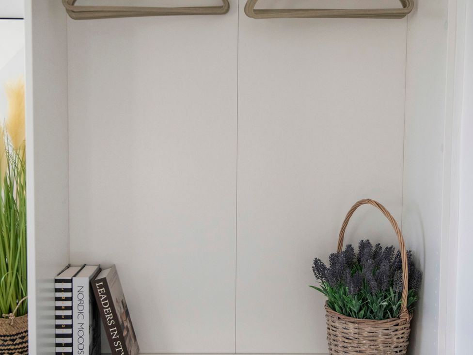 A closet with clothes hangers and a basket of lavender at The Old Boat House Lyme Regis
