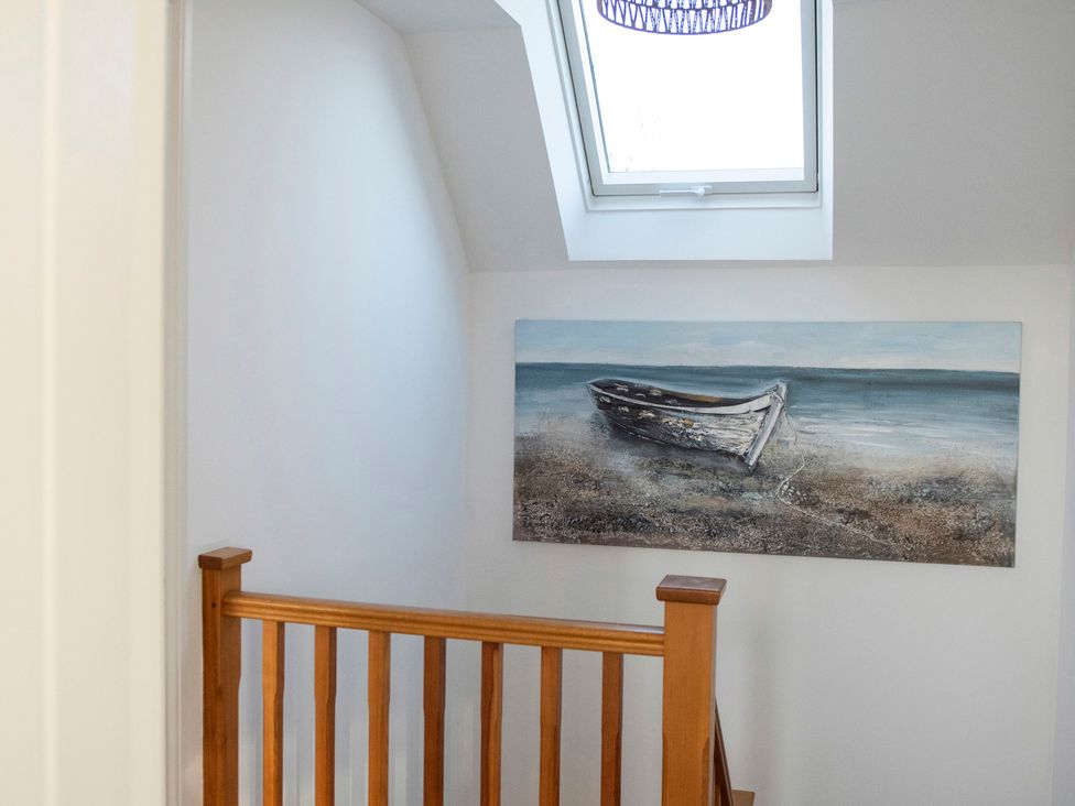 A staircase with a handrail and a painting of a boat at The Old Boat House Lyme Regis