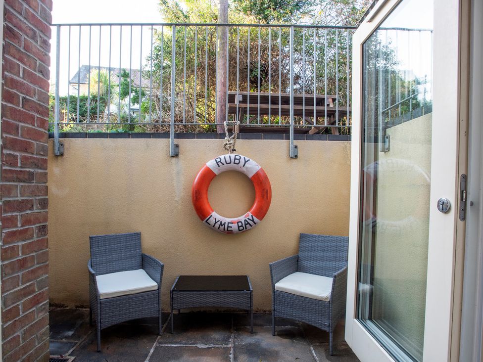 An outdoor area with two chairs, a table, and a lifebuoy at The Old Boat House in Lyme Regis