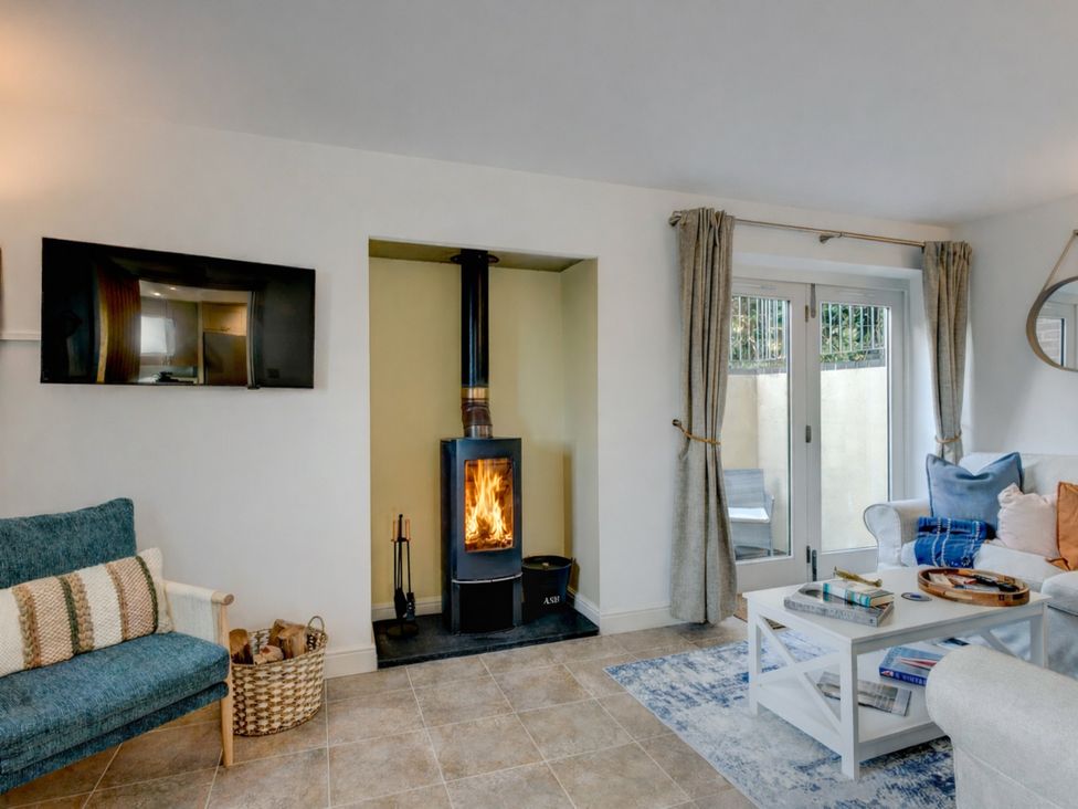 A living room with a wood stove and a television at The Old Boat House in Lyme Regis