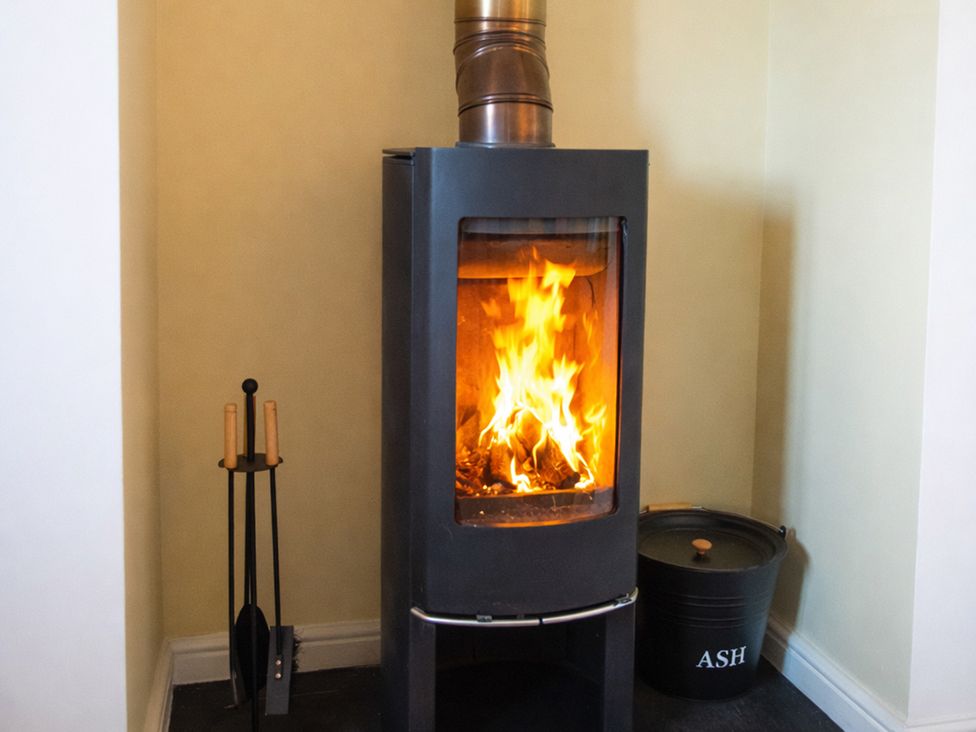 A stove with fire in a living room at The Old Boat House Lyme Regis