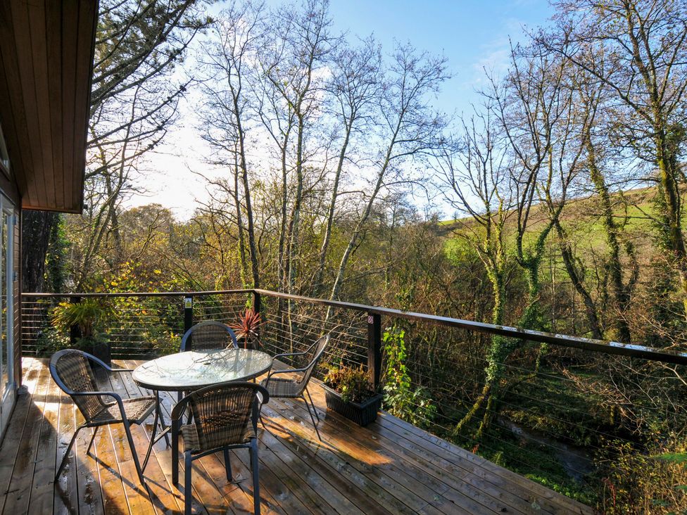 A terrace with a table and chairs overlooking trees at 6 Stonerush Valley Looe