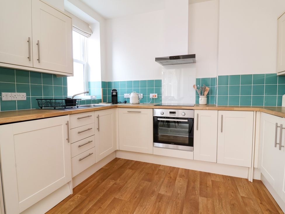 A kitchen with cabinets, an oven, and a sink at The Old Bank Flat in North Tawton
