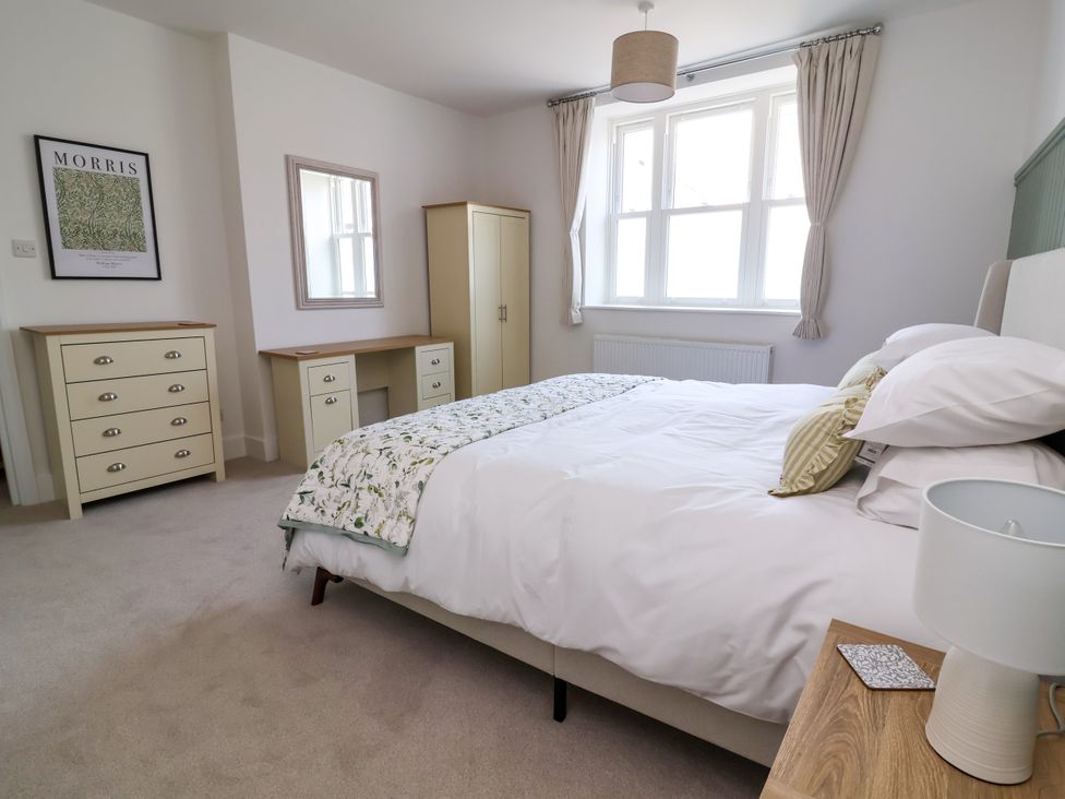 A bedroom with a bed and furniture including a desk and drawers at The Old Bank Flat North Tawton