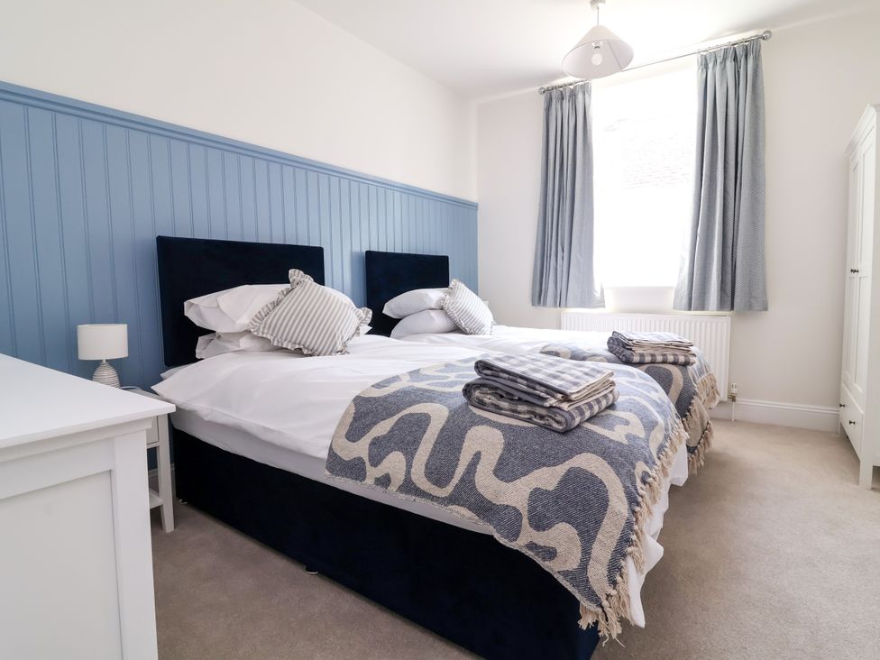 A bedroom with two beds and a wardrobe at The Old Bank Flat in North Tawton