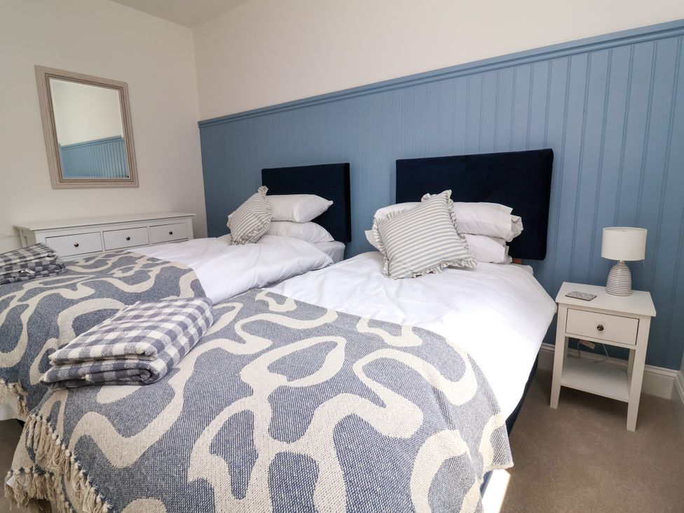 A bedroom with two beds and a nightstand at The Old Bank Flat North Tawton