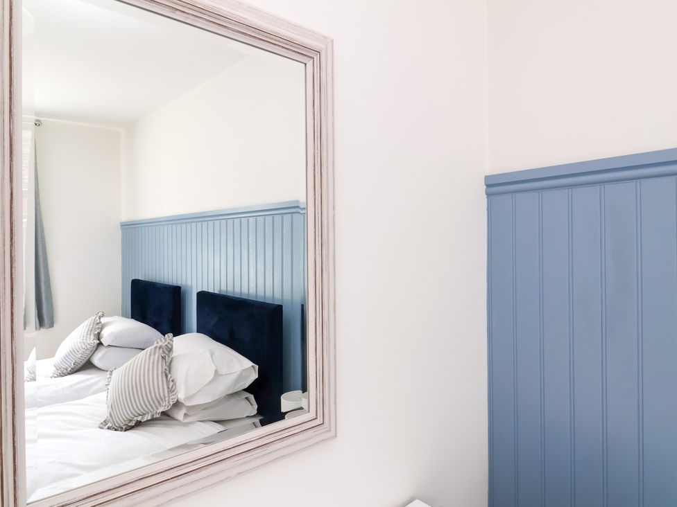 A bedroom with a mirror reflecting a bed at The Old Bank Flat North Tawton