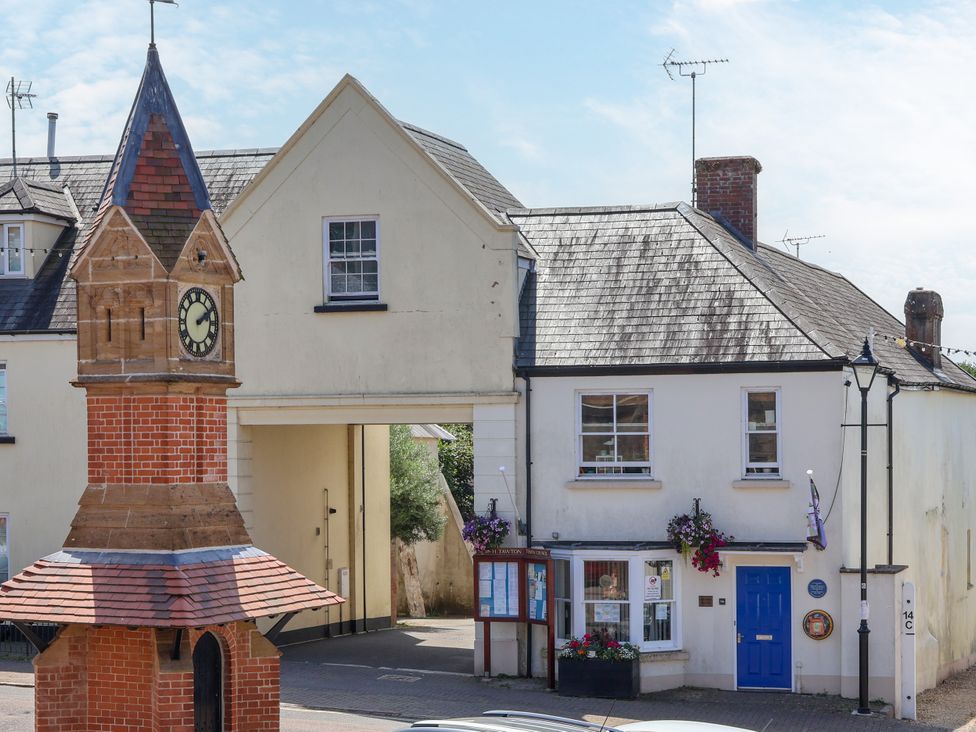 A clock tower and buildings with flowers at The Old Bank Flat in North Tawton