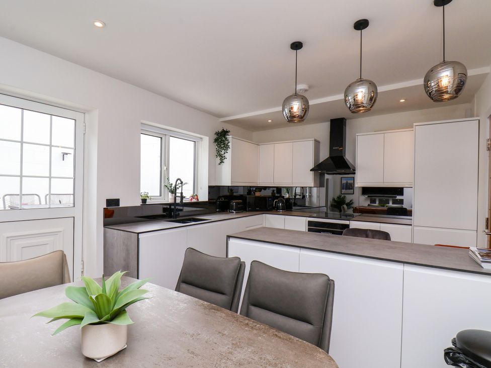 A kitchen with cabinets and a dining table at Og's House in Whitby