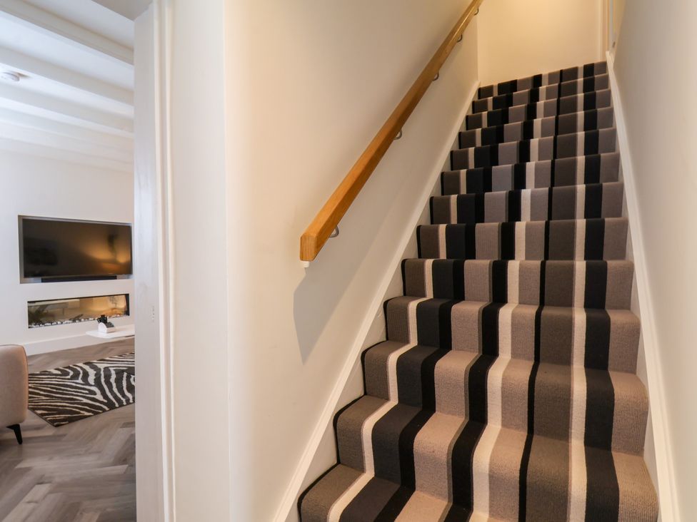 A staircase with a wooden handrail and carpet at Og's House in Whitby