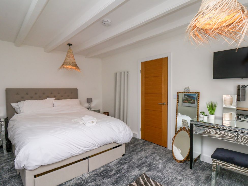 A bedroom with a double bed and mirror at Og's House in Whitby