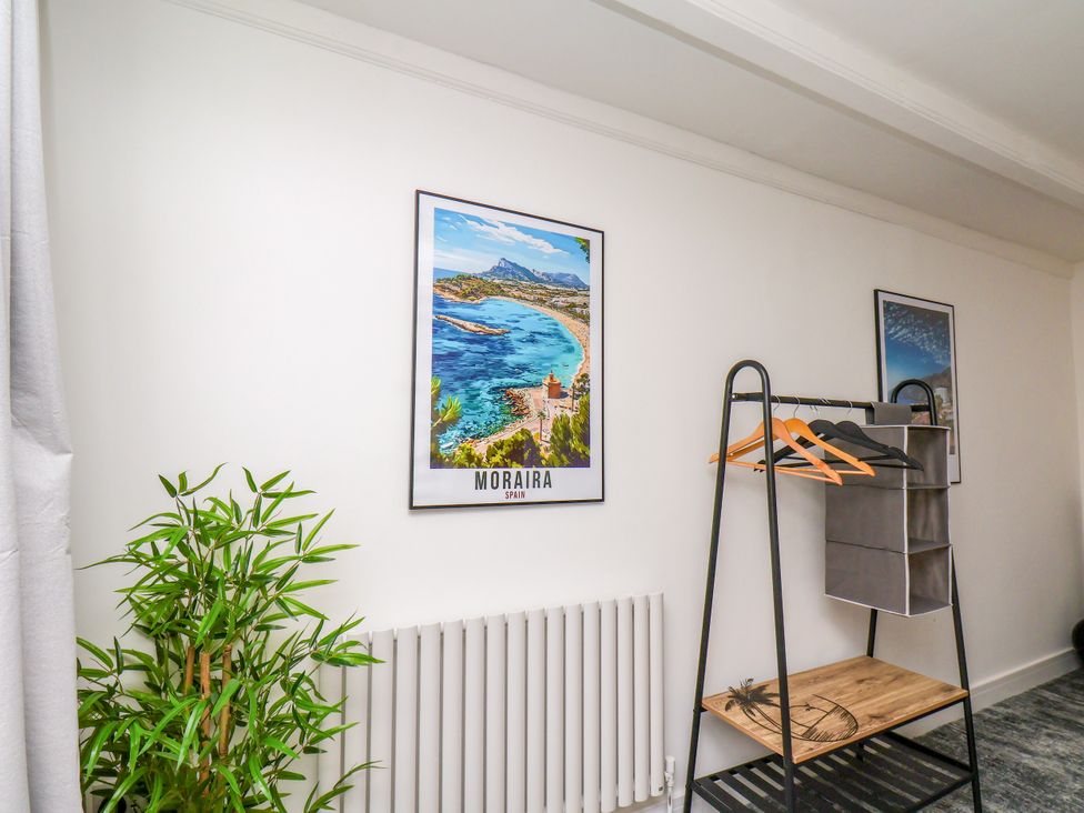 A room with a plant, a poster, a clothes rack, and a radiator at Og's House in Whitby