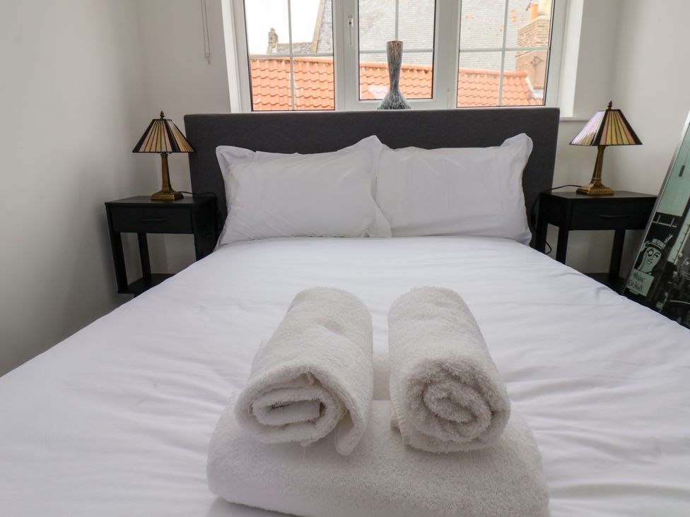 A bedroom with a bed and towels at Og's House in Whitby