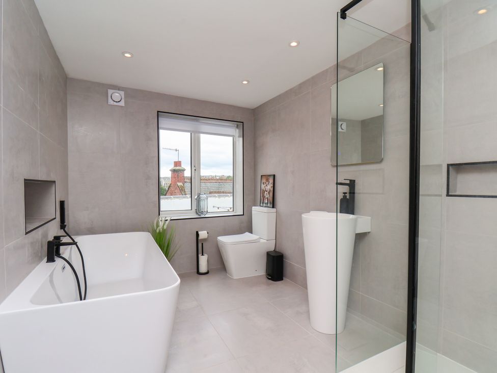A bathroom with a bath tub, toilet, and sink at Og's House in Whitby