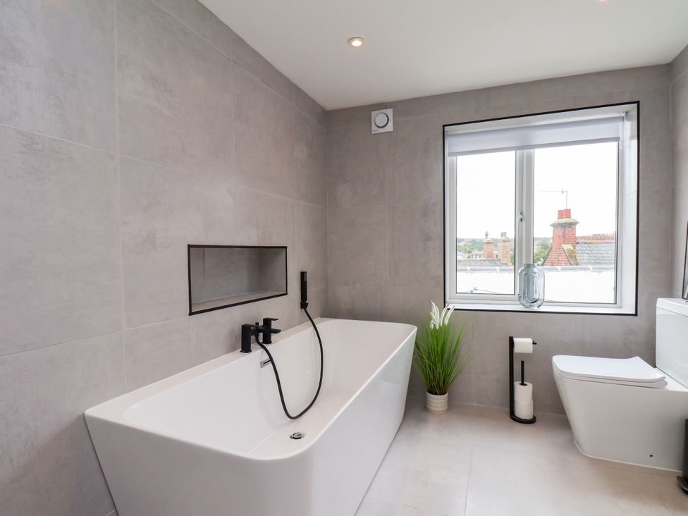 A bathroom with a bathtub and toilet at Og's House in Whitby