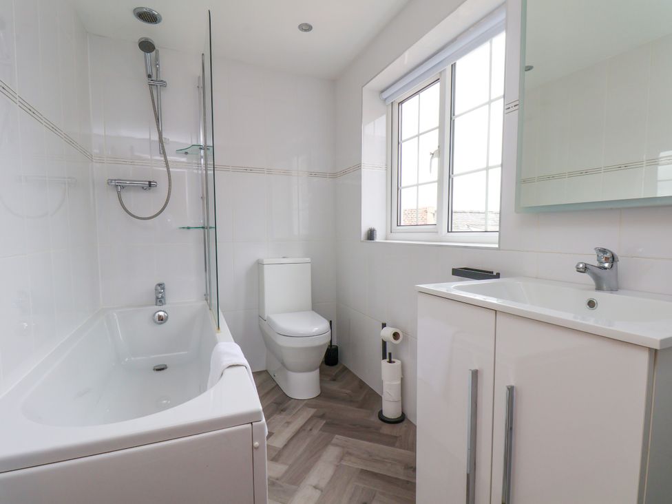 A bathroom with a bathtub, shower, toilet, and sink at Og's House in Whitby