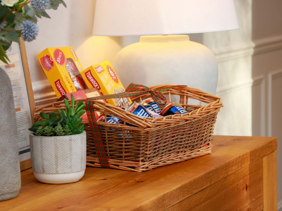 A basket with snacks and a lamp on a table at Cramar Cottage