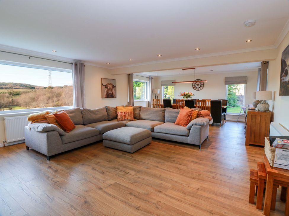 A living room with a large sofa and dining area at Cramar Cottage 