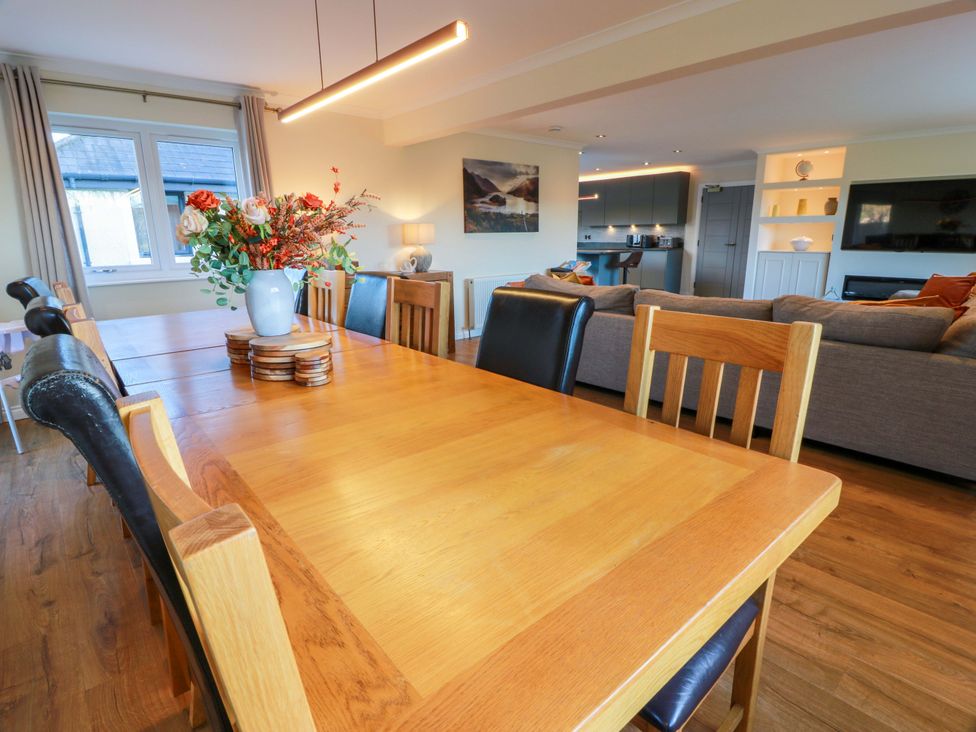 A dining room with a table and flowers at Cramar Cottage