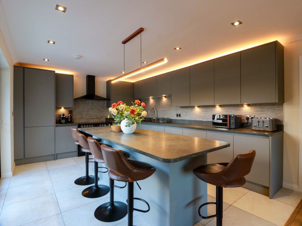 A kitchen with cabinets and stools at Cramar Cottage