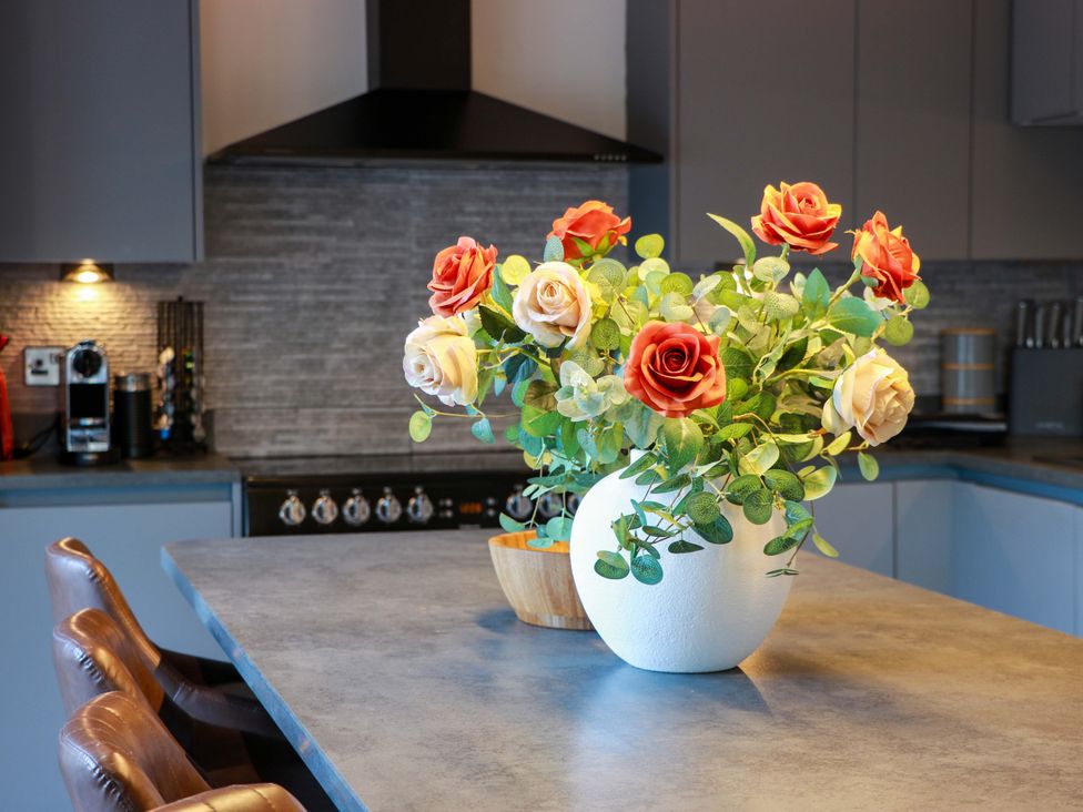 A kitchen with a table and a vase of flowers at Cramar Cottage