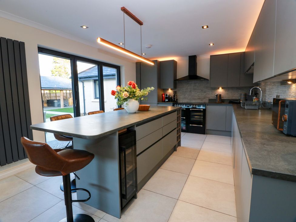 A kitchen with an island and bar stools at Cramar Cottage