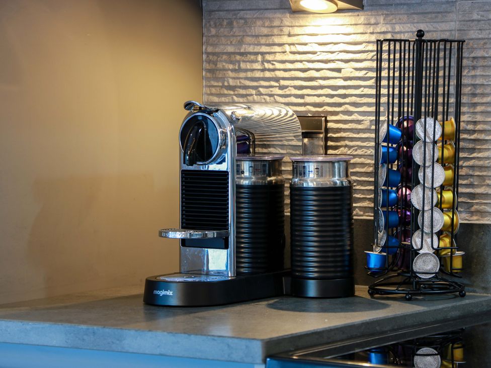 A coffee machine and capsule holder in a kitchen at Cramar Cottage